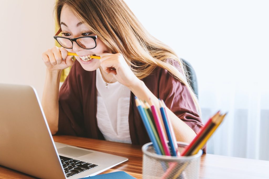 Immagine di ragazza al pc con penna in bocca